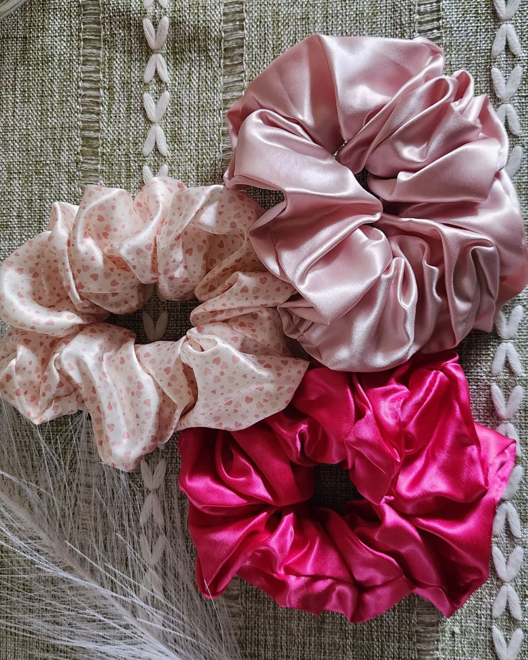 Hand holding an oversized Mulberry silk scrunchie with pastel brushstroke print in pink, purple, and blue tones. Hair accessory by The Scrunchie Vault.