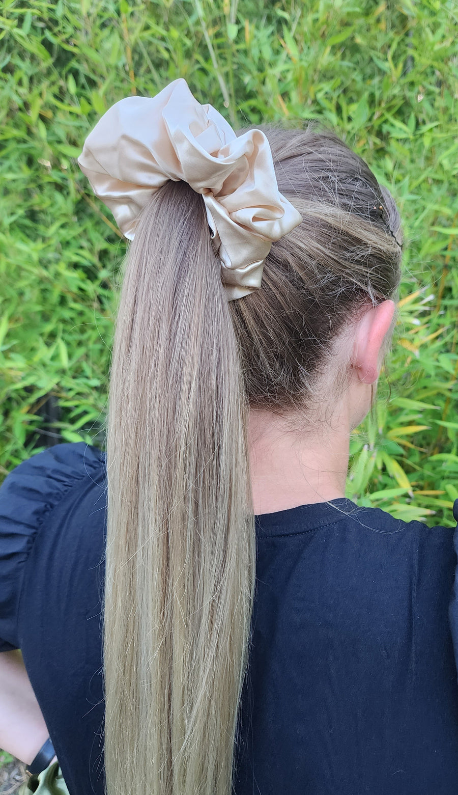 Oat Milk oversized mulberry silk scrunchie in beige cream worn in a blonde ponytail outdoors