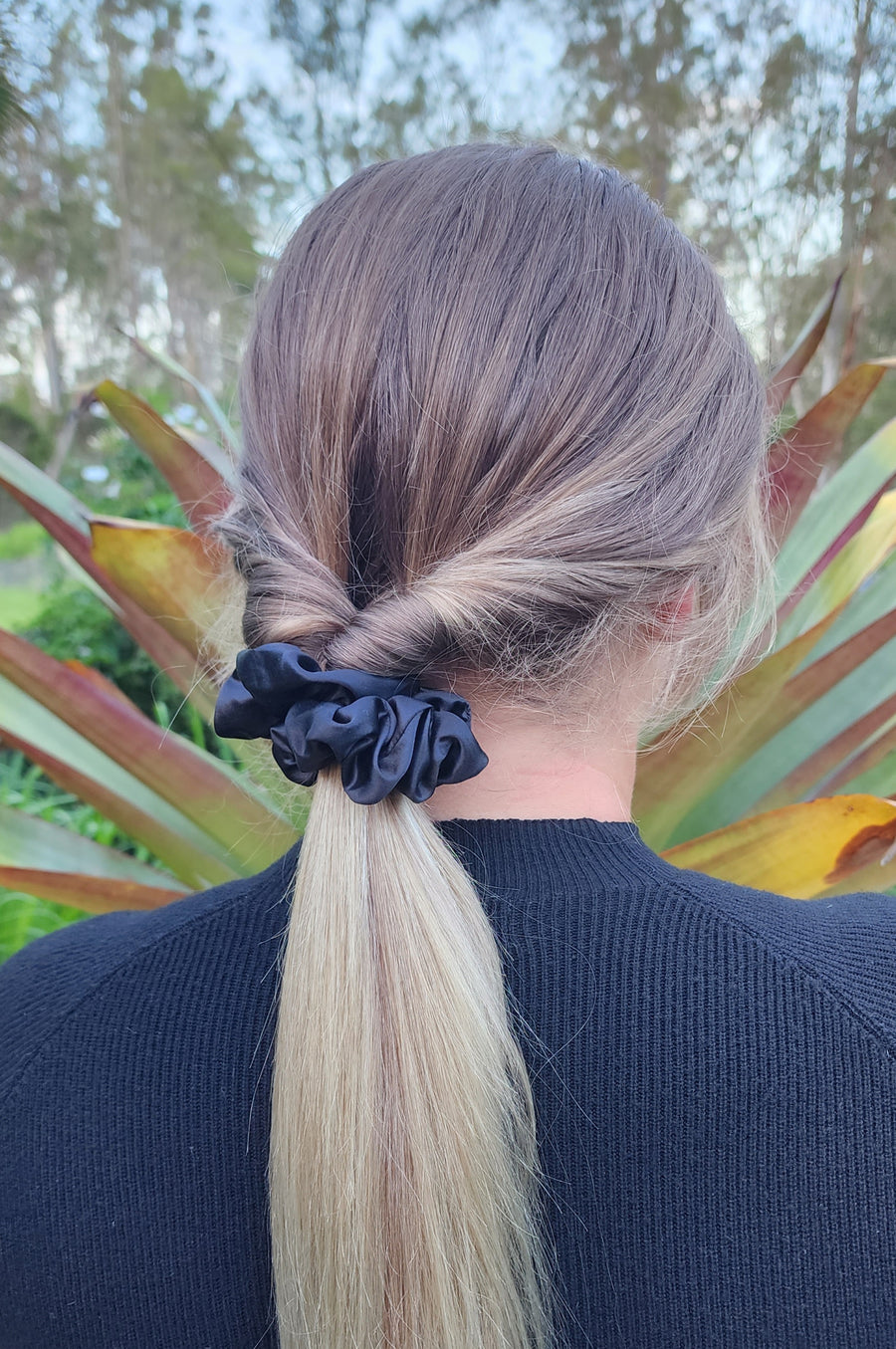 Onyx classic mulberry silk scrunchie in black worn in a blonde ponytail outdoors